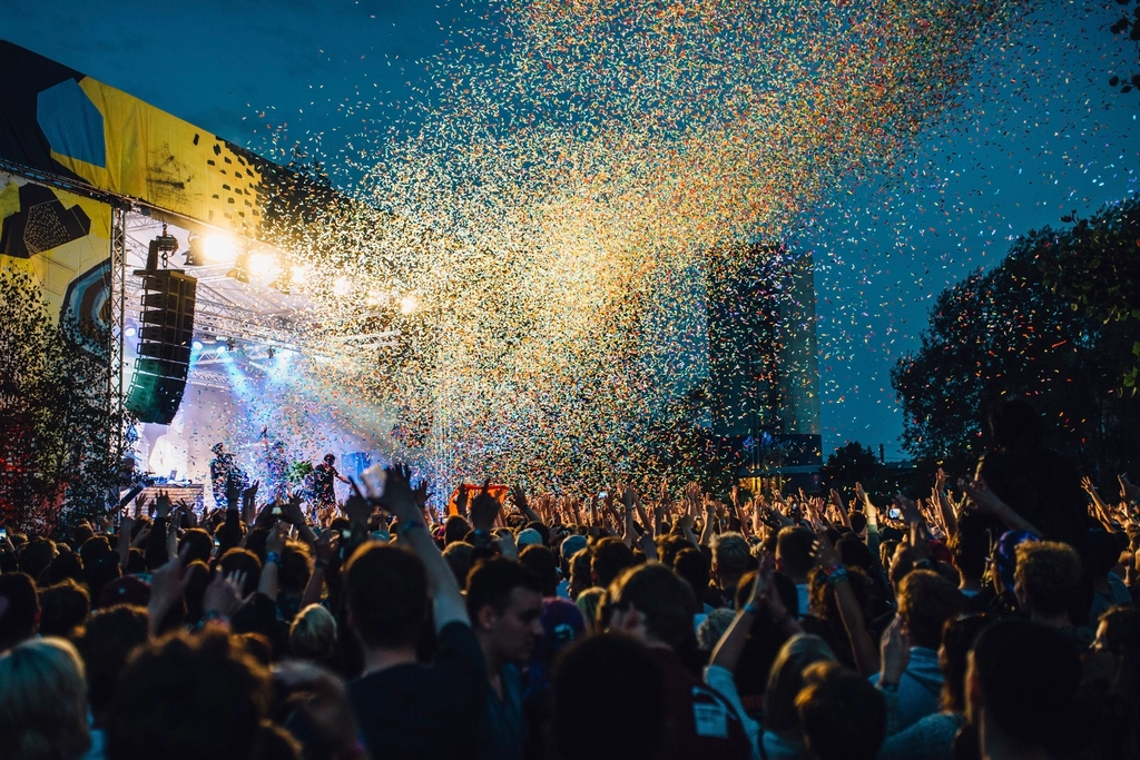 A festival crowd at golden hour, hands raised
